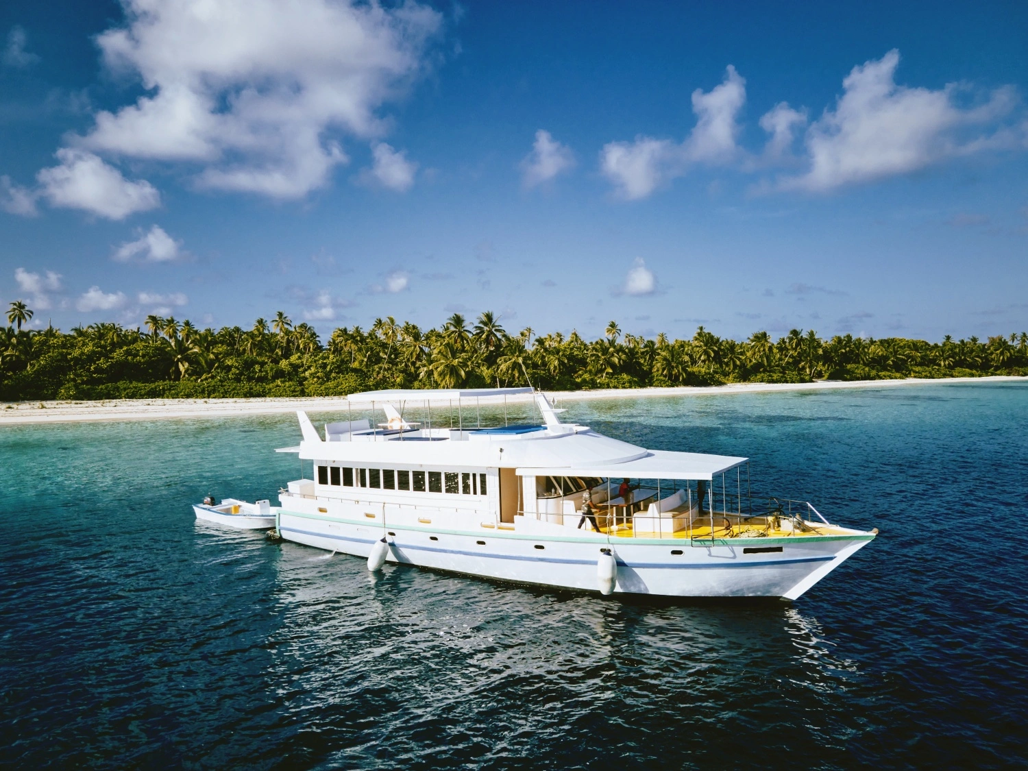 Horizon II surf charter yacht on clear Maldivian water with surf dhoni ready for a break transfer.